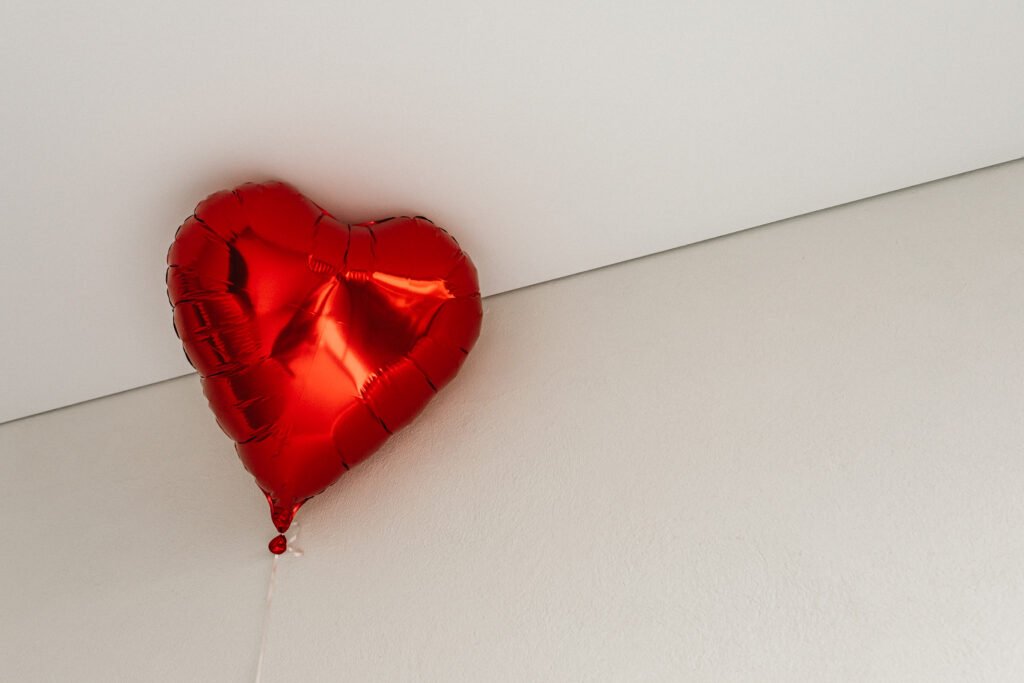 Minimalistic Valentine's Day aesthetic featuring a shiny red heart-shaped balloon.